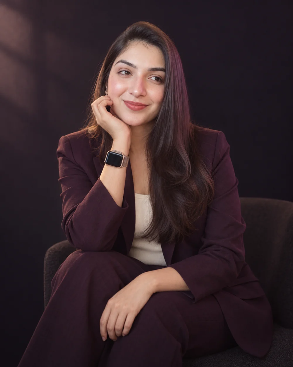 AI-styled editorial portrait of Neha seated against a dark plum backdrop.
